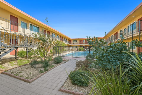 A sunny day at a residential complex with a pool and a well-maintained garden.