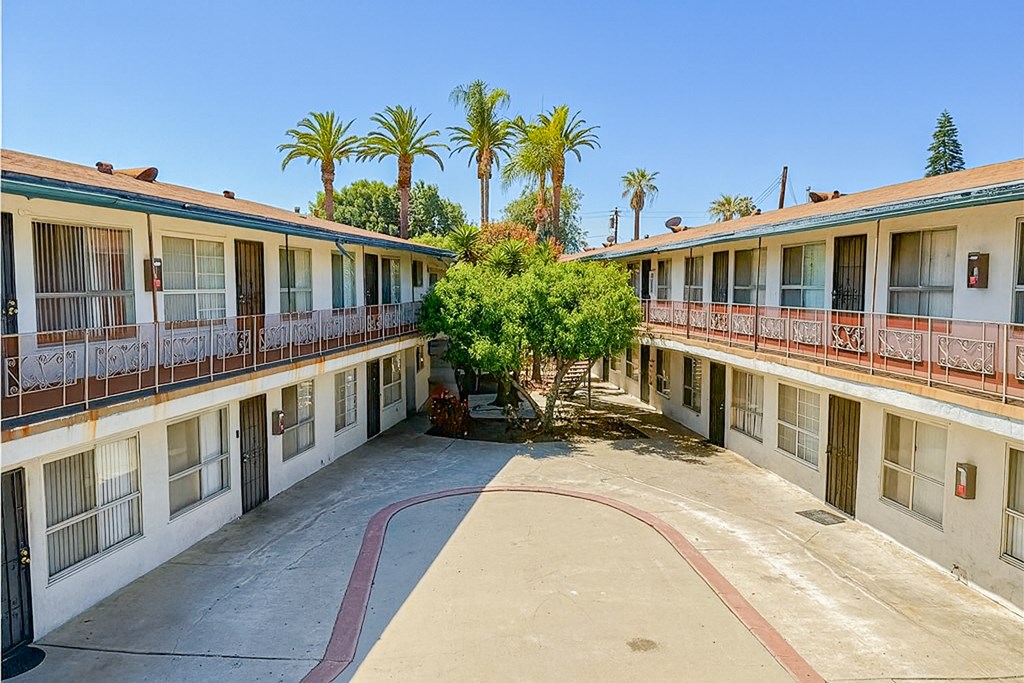 A courtyard with a tree surrounded by buildings with balconies.
