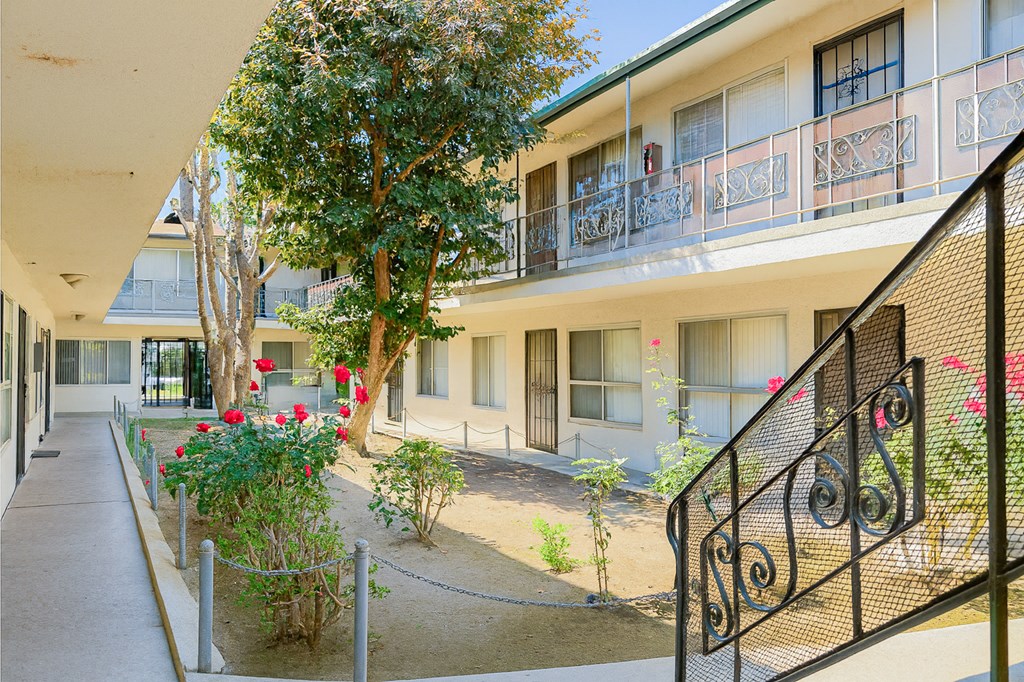 A balcony with a black railing and a tree in front of a building.