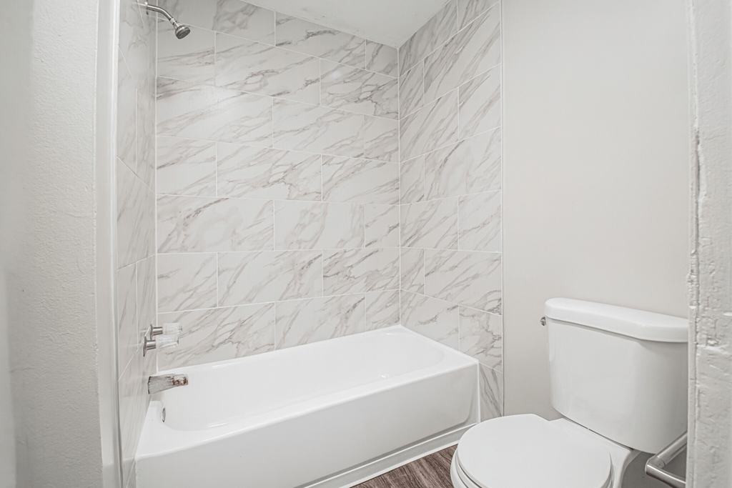 A white bathroom with a marble tile wall.