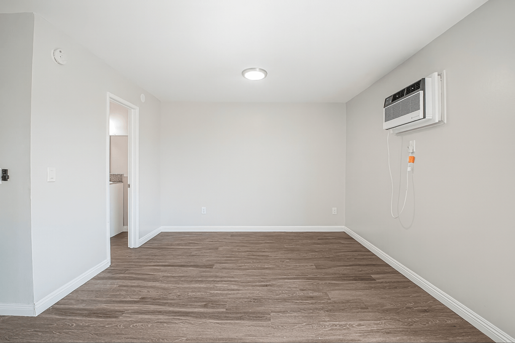 A room with a wood floor and a wall-mounted air conditioner.