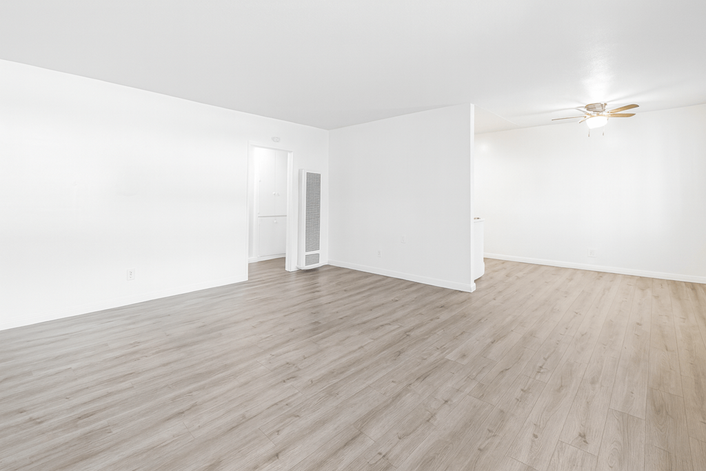 A room with wooden flooring and white walls.