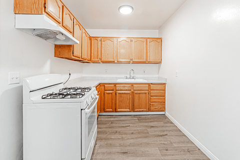 A kitchen with wooden cabinets and a white stove top oven.