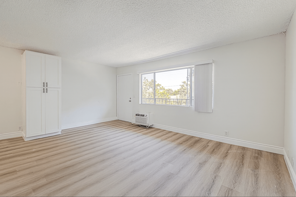 A room with a window and a wooden floor.