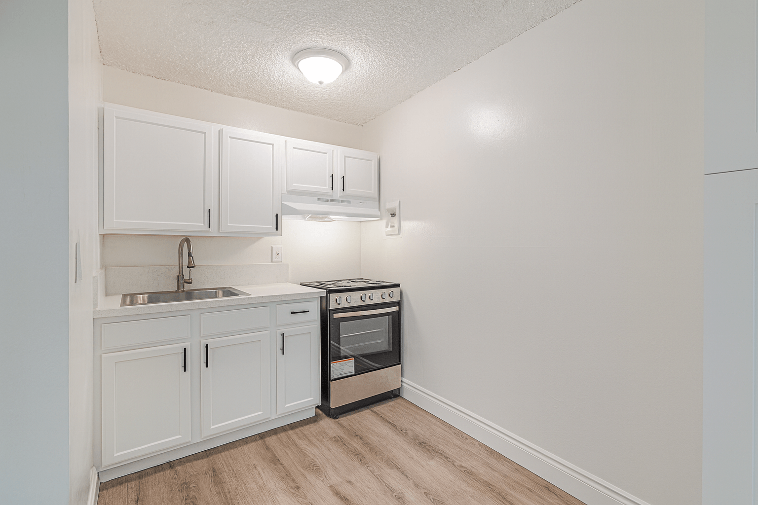 A kitchen with white cabinets and a stove top oven.