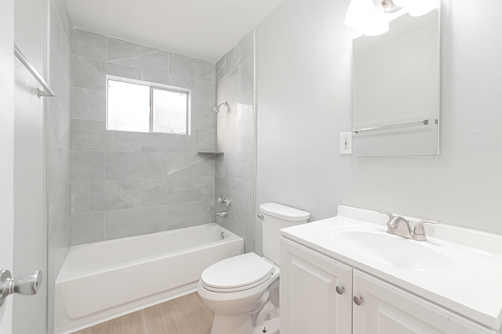 A white bathroom with a toilet, sink, and tub.