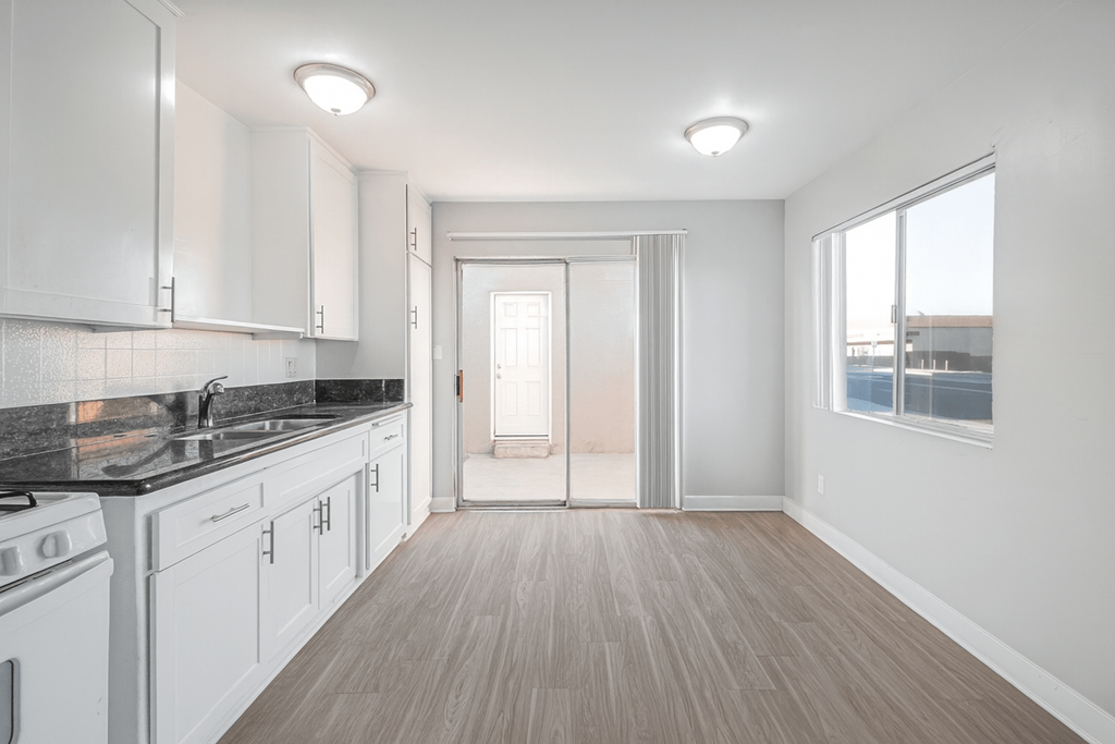 A kitchen with white cabinets and a black countertop.