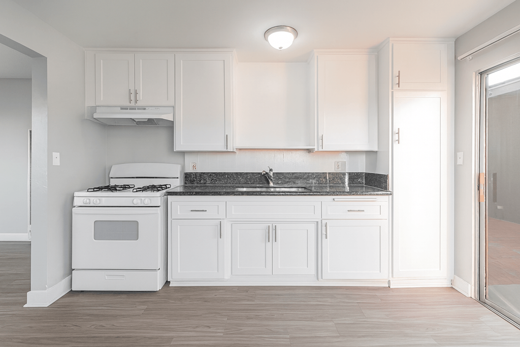 A white kitchen with a stove and cabinets.