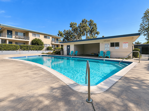 A swimming pool in front of a building with a blue sky in the background.