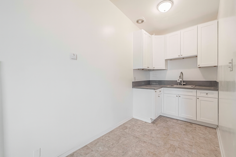 A kitchen with white cabinets and a sink.