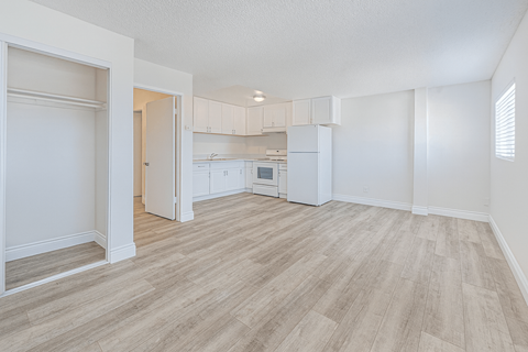 A kitchen area with a refrigerator, sink, and cabinets.