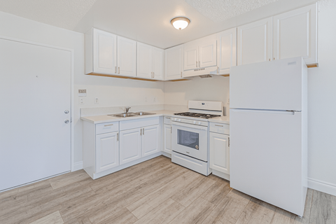 A white kitchen with a refrigerator, stove, and sink.