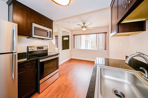 A kitchen with a refrigerator, microwave, sink, and stove.