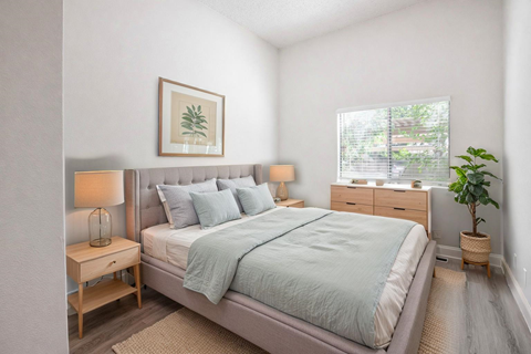 A bedroom with a bed, nightstands, and a plant.
