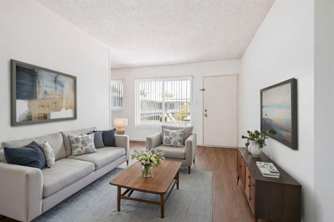 A living room with a grey couch, a coffee table, and a painting on the wall.