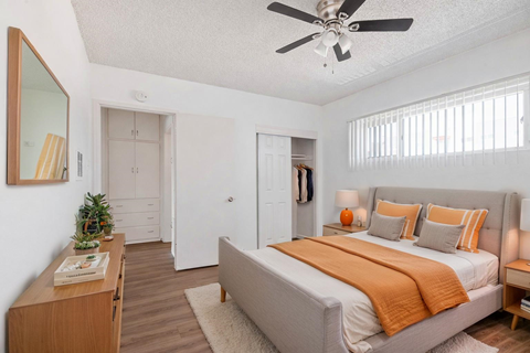 A bedroom with a bed, a ceiling fan, and a wooden nightstand.