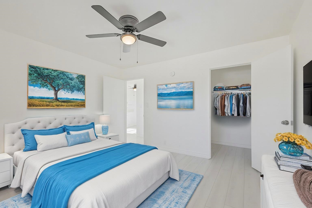 A bedroom with a large bed and a ceiling fan.