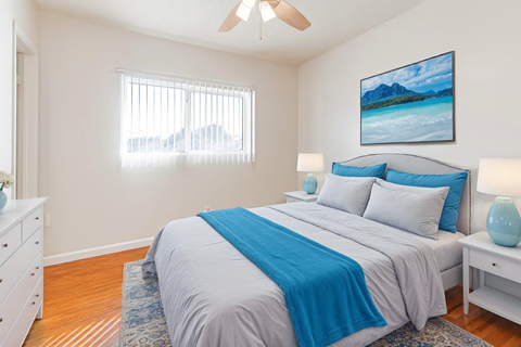 A bedroom with a bed, nightstand, and a painting on the wall.