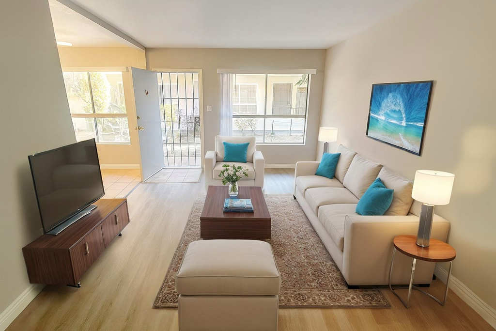 A living room with a white couch, a coffee table, and a television.