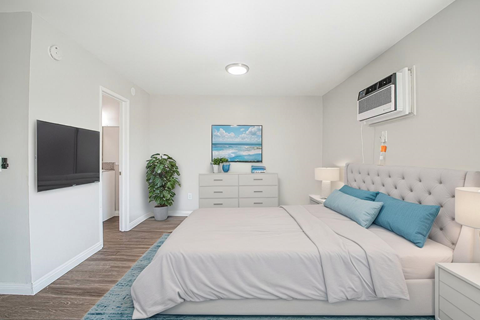 A bedroom with a bed, nightstand, and a painting on the wall.