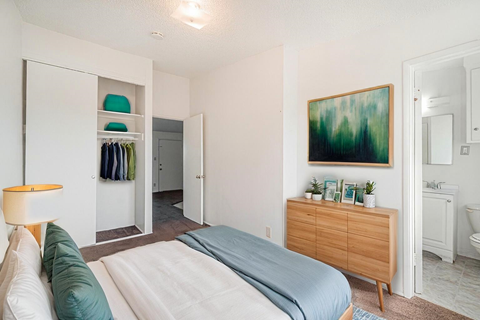 A bedroom with a bed, a dresser, and a painting on the wall.
