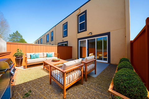 A patio with a table and chairs is surrounded by a wooden fence.