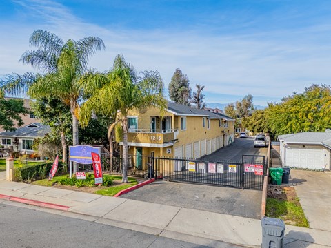A residential street with a house numbered 1219 and a blue sign in front of it.