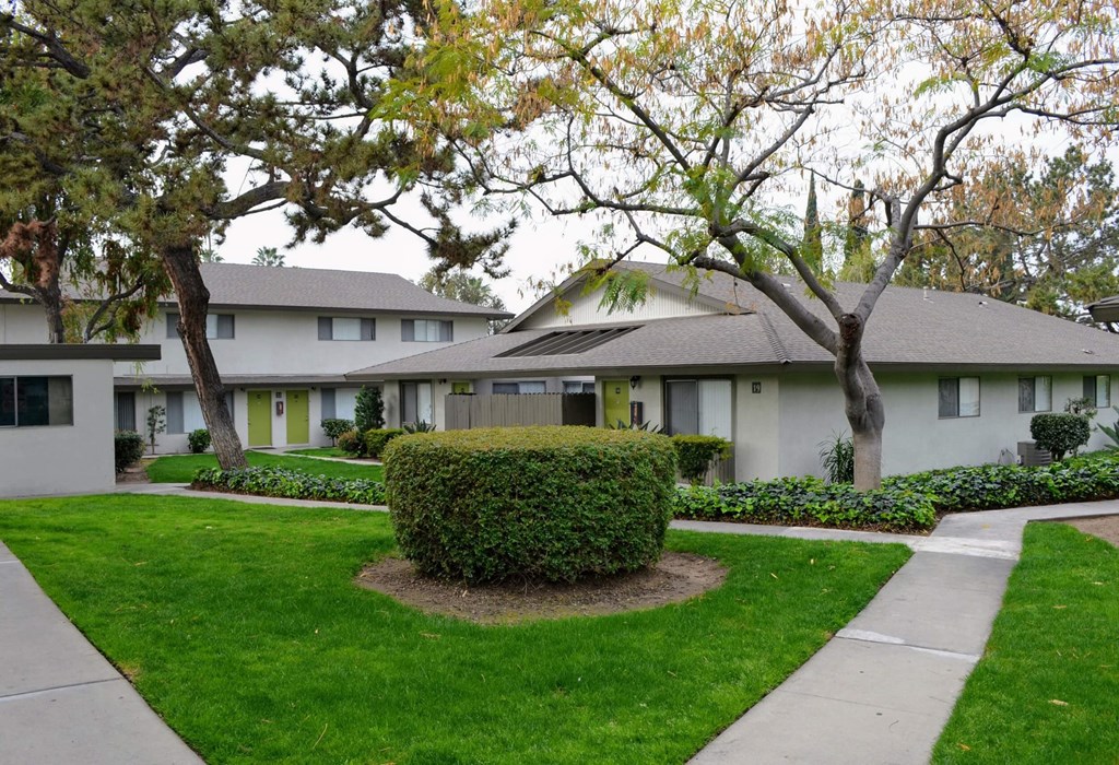 a white house with a lawn and trees in front of it at Terramonte Apartment Homes, Pomona, 91767
