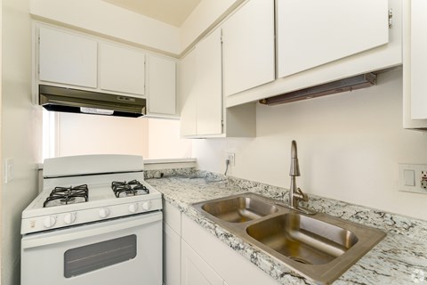 A white kitchen with a stove and sink.