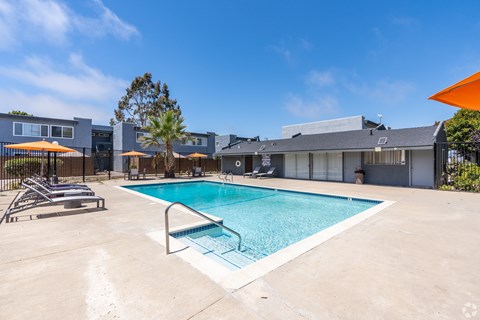 A swimming pool surrounded by a concrete patio and a metal fence.