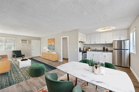 A modern kitchen with a white table and green chairs.