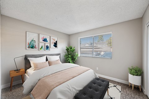 A bedroom with a large bed and a plant on the windowsill.