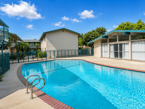 A swimming pool surrounded by a fence and a building in the background.
