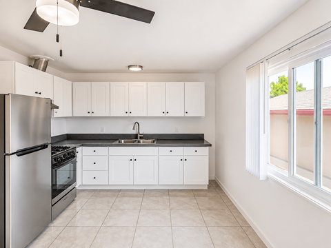 A kitchen with white cabinets and a stainless steel refrigerator.