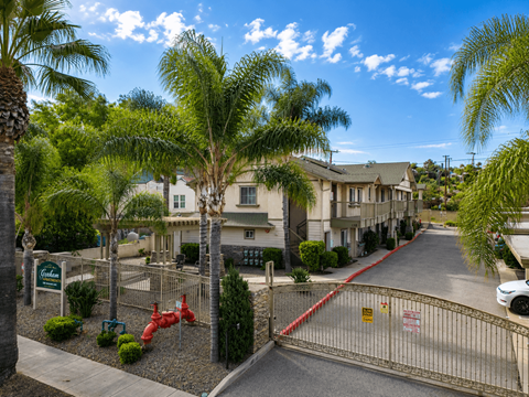 A gated entrance to a residential area with a red fire hydrant.