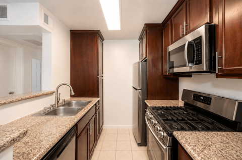 A kitchen with brown cabinets and granite countertops.