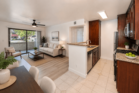 A modern kitchen and living room with white furniture and a ceiling fan.
