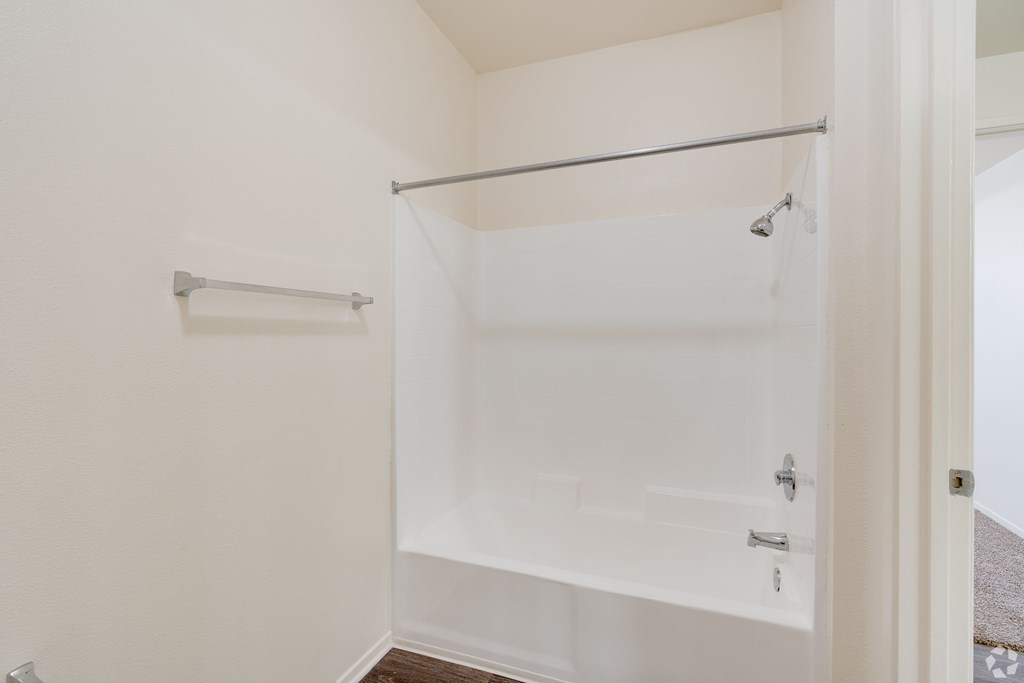 A white shower stall with a glass door and a metal rod above it.
