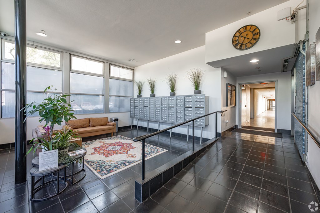 A hallway with a clock on the wall and a railing on the floor.