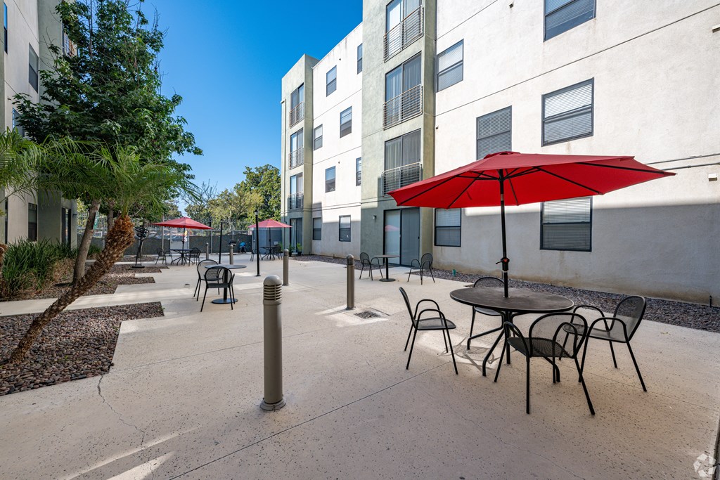 A red umbrella is on a table outside a building.