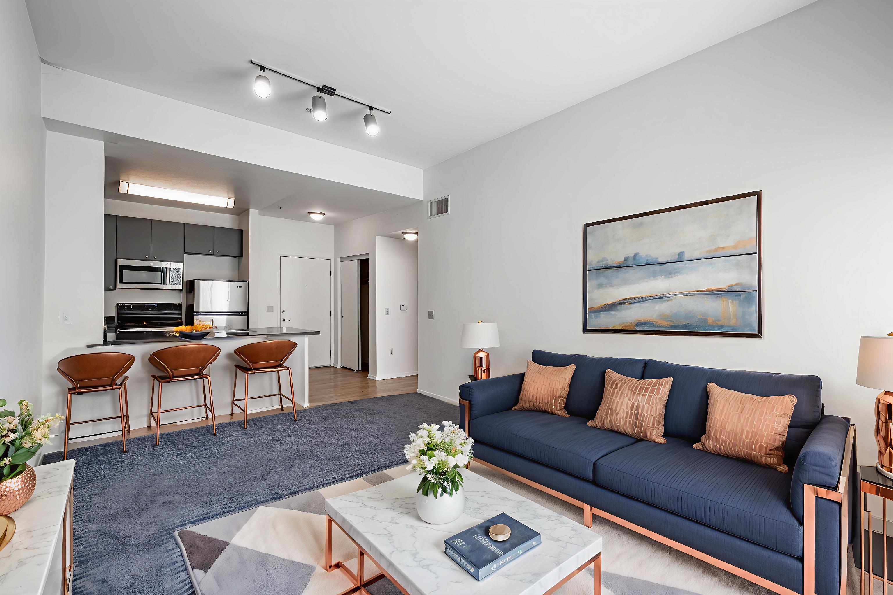 A living room with a blue couch and a painting on the wall.