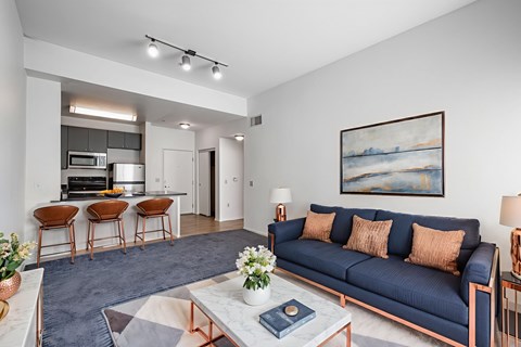 A living room with a blue couch and a painting on the wall.