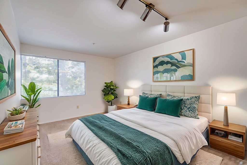 A bedroom with a large bed and a painting on the wall.