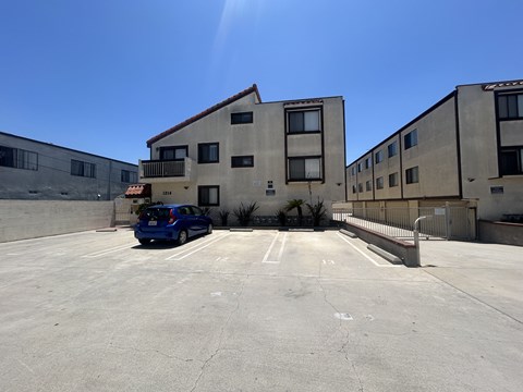 A blue car is parked in a parking lot in front of a building.