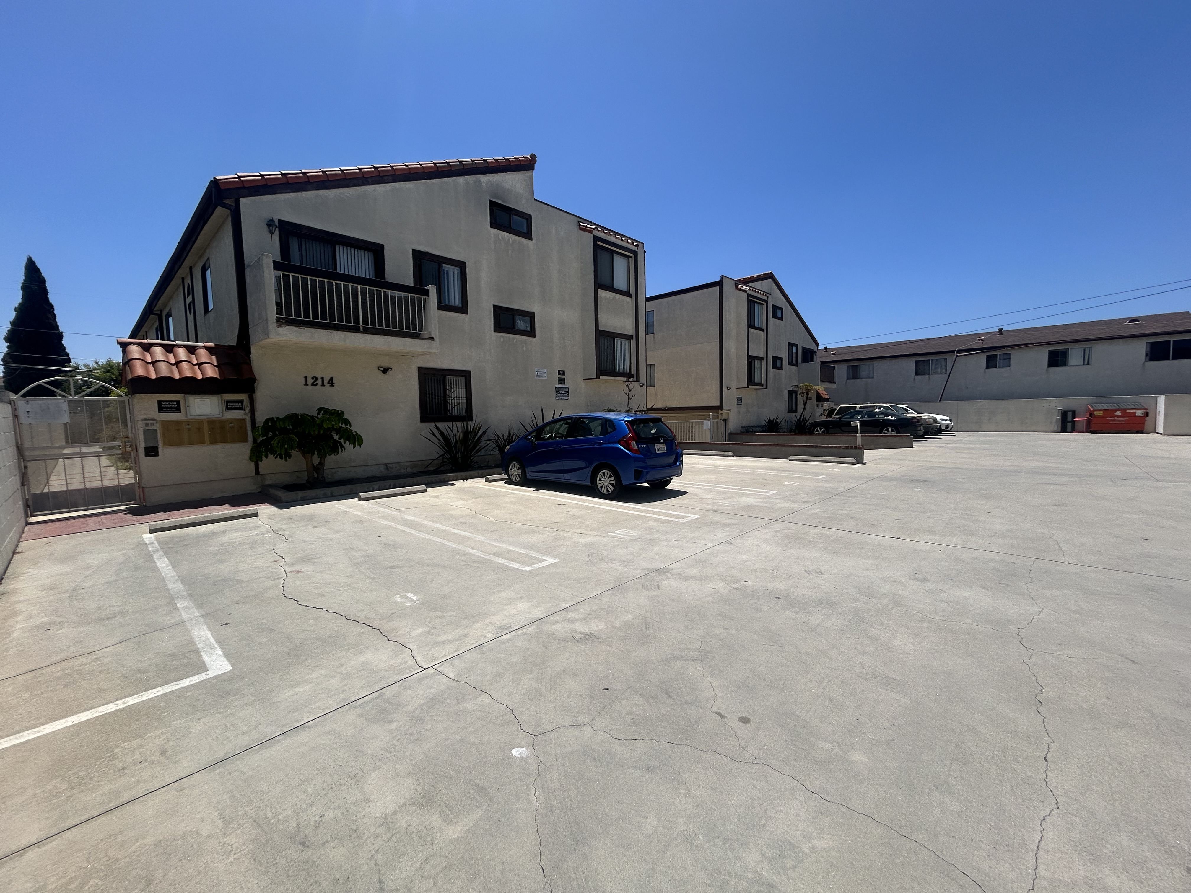 A parking lot with a building and a car.