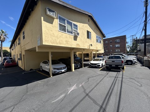 A yellow building with a parking lot in front of it.