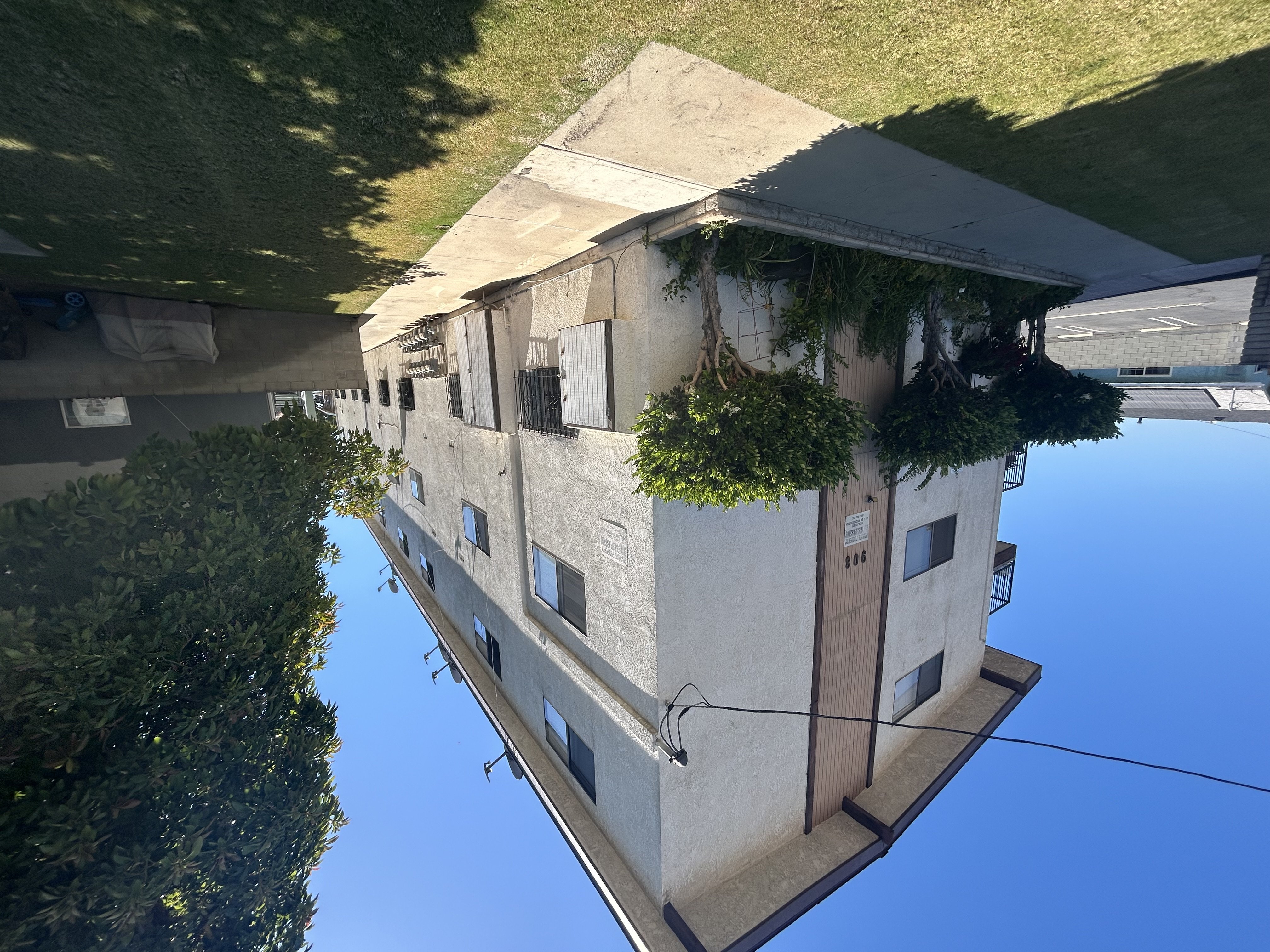 A building with a green plant on the side is reflected in the water.