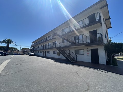 A sunny day at a parking lot with a building in the background.