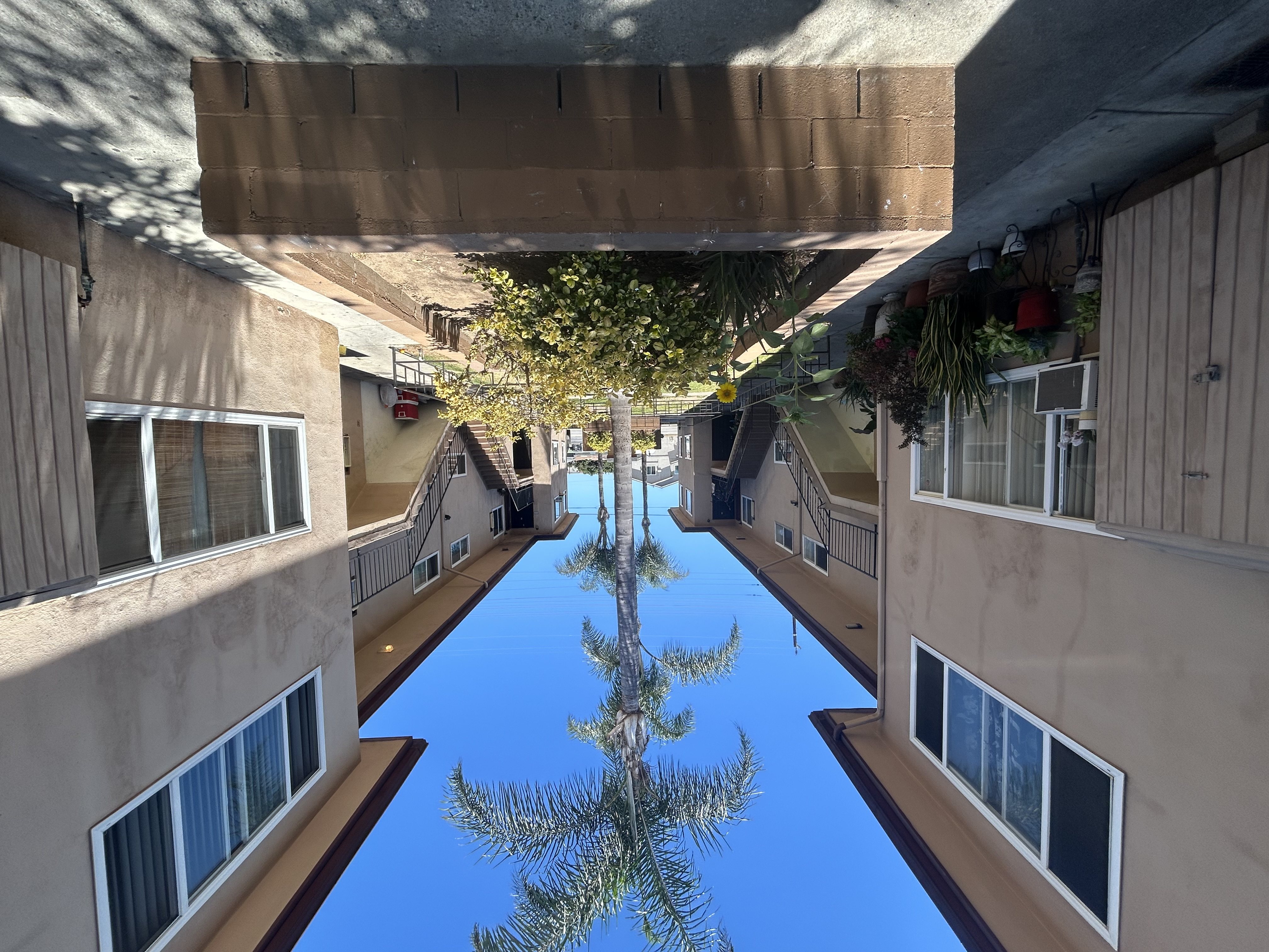 A long, narrow pool of blue water is surrounded by buildings on both sides.