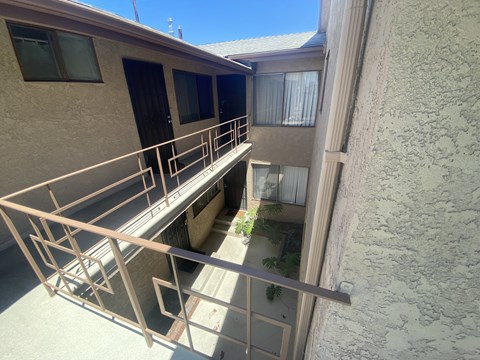 A balcony with a metal railing and a small garden area.